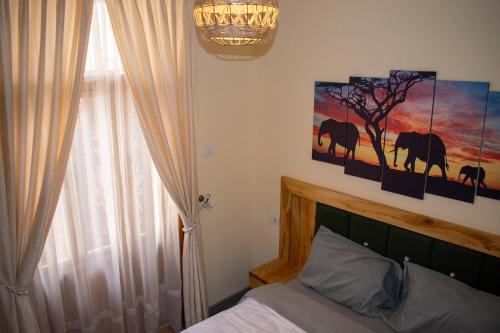 a bedroom with a bed with two paintings on the wall at Choice Guest House 2 in Addis Ababa