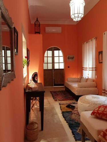 un soggiorno con pareti arancioni, un divano e un tavolo di Dar al Sultan a Marrakech