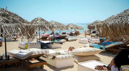 アヤナパにあるDome Beach Marina Hotel & Resortの多くのベッドとわらパラソルが備わるビーチ