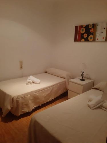 a bedroom with two beds and a table and a painting at Apartamento Sagunto frente a Renfe in Sagunto
