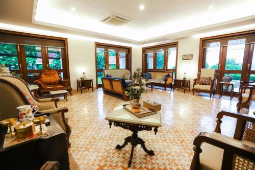 a living room filled with lots of furniture and windows at Saptapuri by Royal Orchid Hotels Limited Varanasi in Varanasi