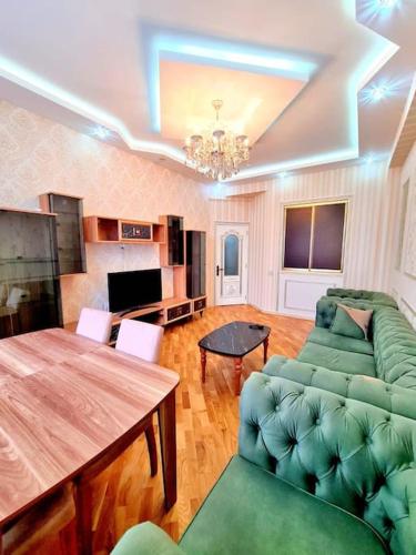 a living room with a green couch and a table at Премиум квартира возле метро in Baku