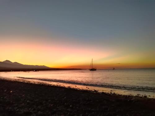 a boat in the water at sunset on the beach at beach side Amed Delem family in Amed