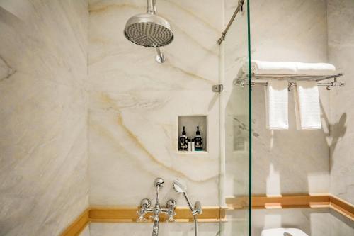 a shower with a glass door in a bathroom at Saptapuri by Royal Orchid Hotels Limited Varanasi in Varanasi