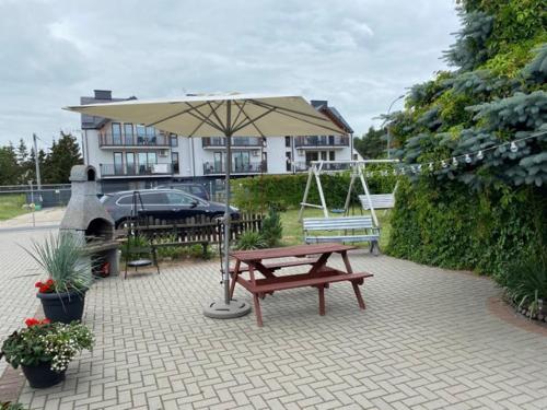 a picnic table and an umbrella in front of a house at Apartamenty na Zaciszu in Kąty Rybackie