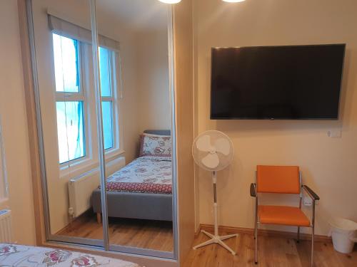 a room with a tv and a chair and a mirror at London Luxury Spacious 2 Bedroom Apartment 4 mins from Ilford Stn. FREE parking in London