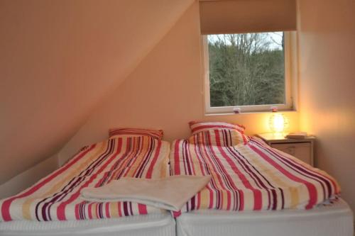 a bed with a striped blanket and a window at Relaxhouse in Håkantorp