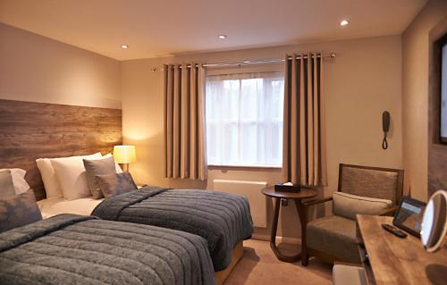 a hotel room with two beds and a desk at Drift Inn formerly the Waterfront Hotel in Saint Neots