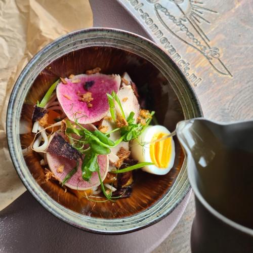 a bowl of food with meat and eggs on a table at Sonnevanck Wijk aan Zee in Wijk aan Zee
