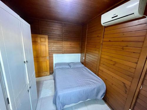a small bedroom with a bed in a wooden room at Cabana com piscina - 5 min a pé da praia - Porto Belo in Porto Belo