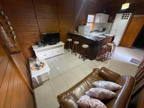 a living room with a leather couch and a kitchen at Cabana com piscina - 5 min a pé da praia - Porto Belo in Porto Belo
