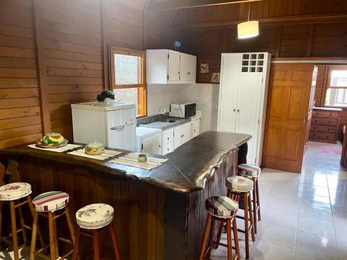 a kitchen with a large counter with stools in it at Cabana com piscina - 5 min a pé da praia - Porto Belo in Porto Belo