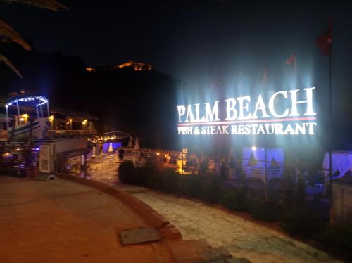 a sign that says palm beach for avery restaurant at night at Beautiful Sultan House at Cleopatra beach 1 with umbrellas, balcony, barbecue, private 100mbps WiFi, smart TV, table games, WhatsApp Support in Alanya
