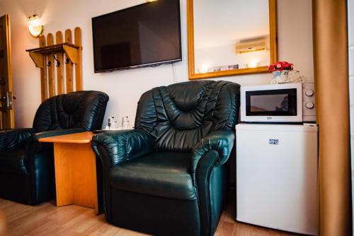 a living room with a black leather chair and a television at Pensiune Roua 2 in Arad