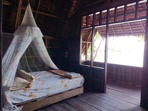 Cama en habitación con mosquitera en Warahnus dive homestay en Kri