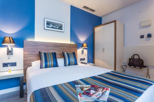 a hotel room with a bed with a magazine on it at DWO Urban Granada in Granada