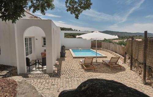 a patio with a swimming pool and an umbrella at Casa do Brasão in Marvão