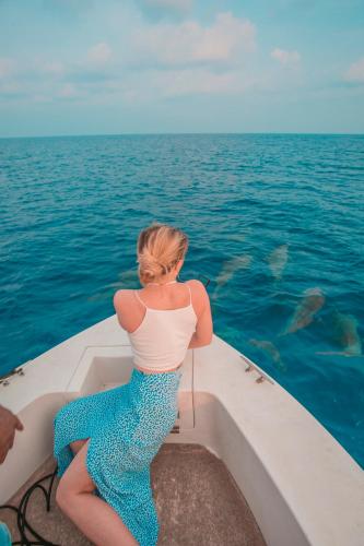 a woman sitting on a boat in the water at Hondaafushi Island Resort in Vaikaradhoo