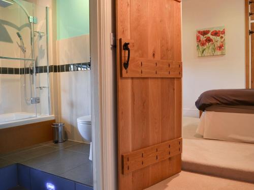 a bathroom with a shower and a wooden door at Isobels Cottage in Chapelton