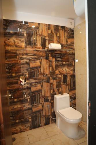 ein Badezimmer mit einem WC und einer Holzwand in der Unterkunft Hotel Cordelia inn in Rishikesh