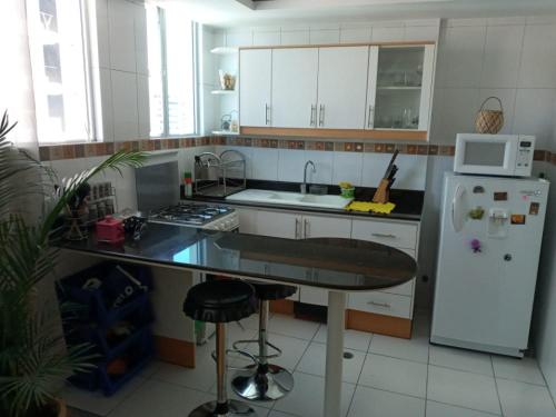 a kitchen with a white refrigerator and a counter top at Bella Suit amoblada, sector exclusivo La Carolina. in Quito
