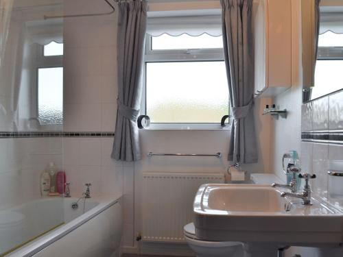 a bathroom with a sink and a toilet and a window at The Flat in Eaton