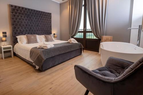 1 dormitorio con 1 cama grande y bañera en Montalbera Wine Suites en Montemagno