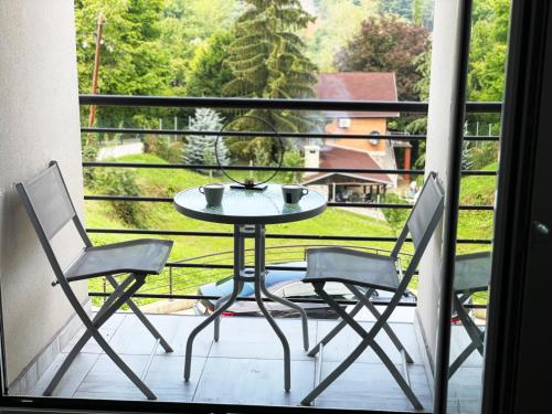 uma mesa e 2 cadeiras numa varanda com vista em Vila Una Fruška gora em Novi Sad