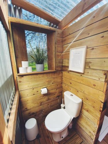 a wooden bathroom with a toilet and a window at White House on Wye Glamping in Brockhampton