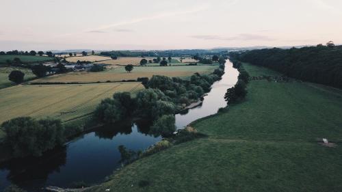 an aerial view of a river with fields and trees at White House on Wye Glamping in Hereford