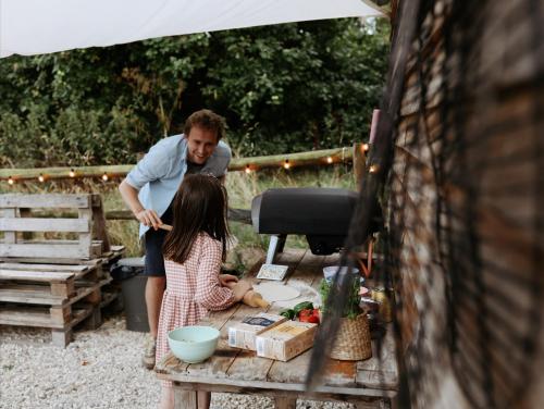 a man standing next to a little girl on a table at White House on Wye Glamping in Hereford