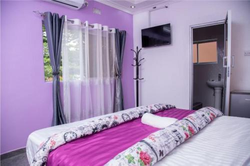 um quarto com paredes roxas e uma cama grande em Kasbek Lodge & Tours em Kazungula