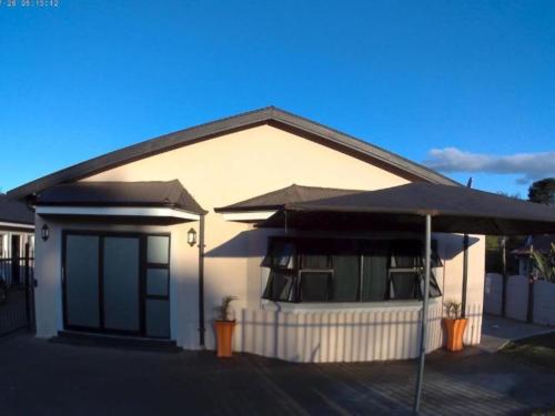 a white house with a porch and a roof at Slee Guest House in Howick