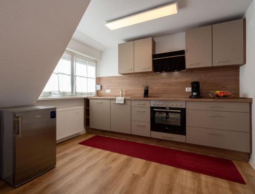 a kitchen with white cabinets and a red rug at Relax Hotel & SPA Stuttgart in Stuttgart