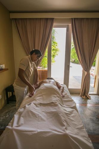 a woman standing over a man laying on a bed at Hondaafushi Island Resort in Vaikaradhoo