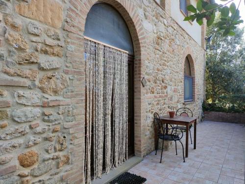 a patio with a table and a stone wall at Agriturismo Fattoria Lischeto in Volterra