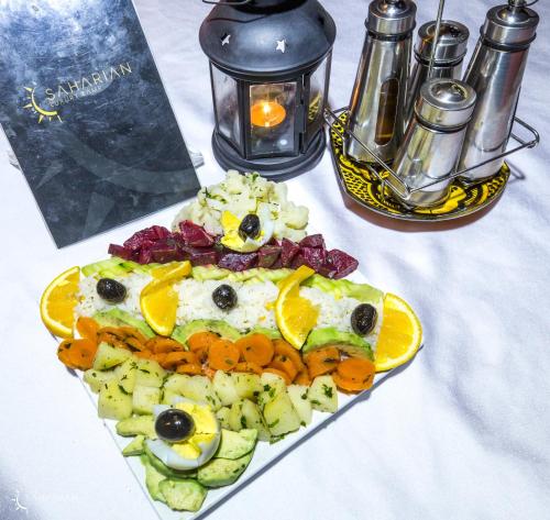 a plate of food with an egg and fruit on a table at Saharian Luxury Camp Deluxe Familly Quadriple in Merzouga