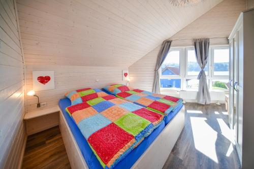 Un dormitorio con una cama con una colcha colorida. en Nordic Ferienpark Sorpesee (Sauerland) en Sundern