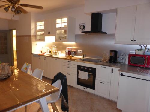 a kitchen with white cabinets and a table with chairs at CASA DOS AVOS in Cabanas de Tavira