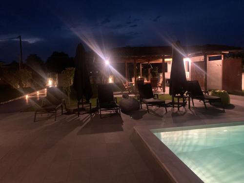a patio with chairs and a swimming pool at night at Luxury Villa Plaka Litochorou with Pool in Plaka Litochorou