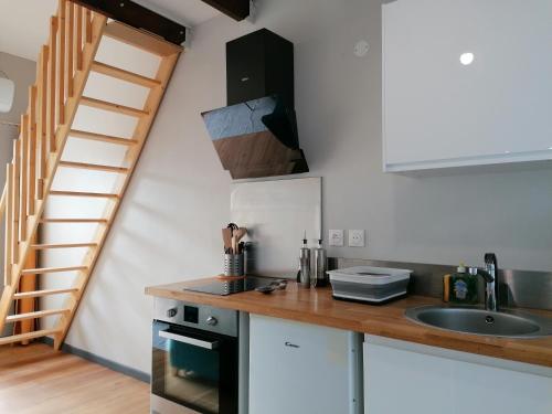 a kitchen with a counter with a sink and a staircase at Le Langka in Saint-Louis