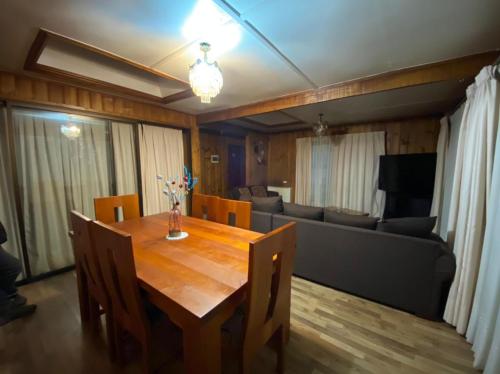 a dining room with a wooden table and a couch at Hostal Y Cabañas Don Juan in Villarrica