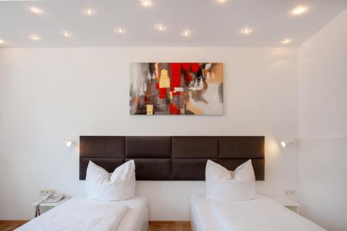 a bedroom with two beds and a painting on the wall at Relax Hotel & SPA Stuttgart in Stuttgart