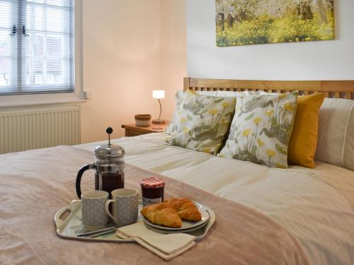 taca śniadaniowa z rogalikami i filiżankami kawy na łóżku w obiekcie Manor Cottage w mieście Findon