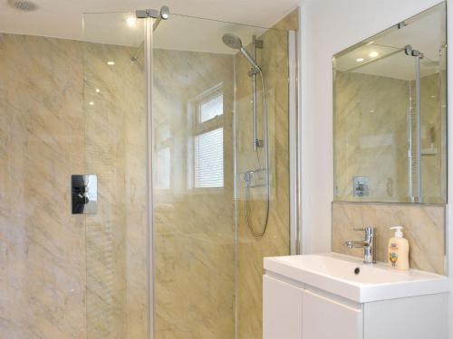 a bathroom with a glass shower with a sink and a shower at Manor Cottage in Findon