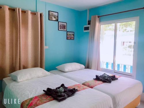 Cette chambre comprend 2 lits dans une chambre dotée de murs bleus et d'une fenêtre. dans l'établissement Baan seefa homestay kohyaoyai, à Ko Yao Yai
