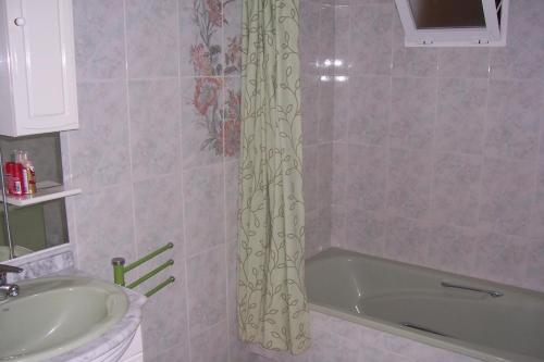ein Badezimmer mit einer Badewanne, einem Waschbecken und einem Duschvorhang in der Unterkunft Pensión Nomphosumus in La Cala del Moral