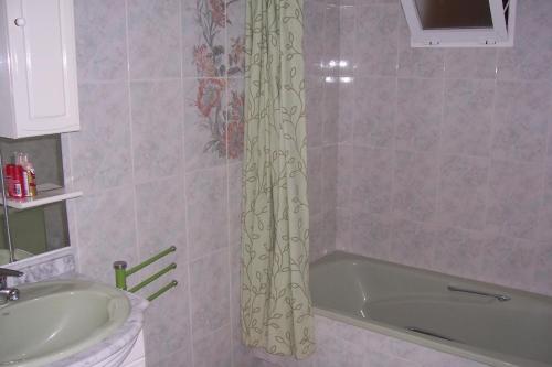a bathroom with a tub and a sink and a shower curtain at Pensión Nomphosumus in Cala del Moral