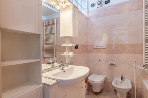 Baño blanco con lavabo y aseo en Appartamento Tra i Due Laghi, en Baselga di Pinè