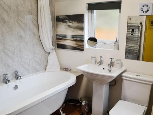 a bathroom with a tub and a sink and a toilet at Fairground Cottage in Rothbury